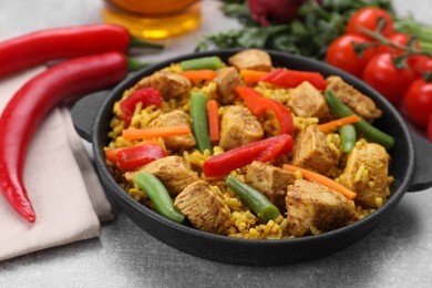 Photo of Delicious rice and chicken served with vegetables on light grey table, closeup