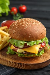 Delicious burger with beef patty, tomato sauce and french fries on dark table, closeup