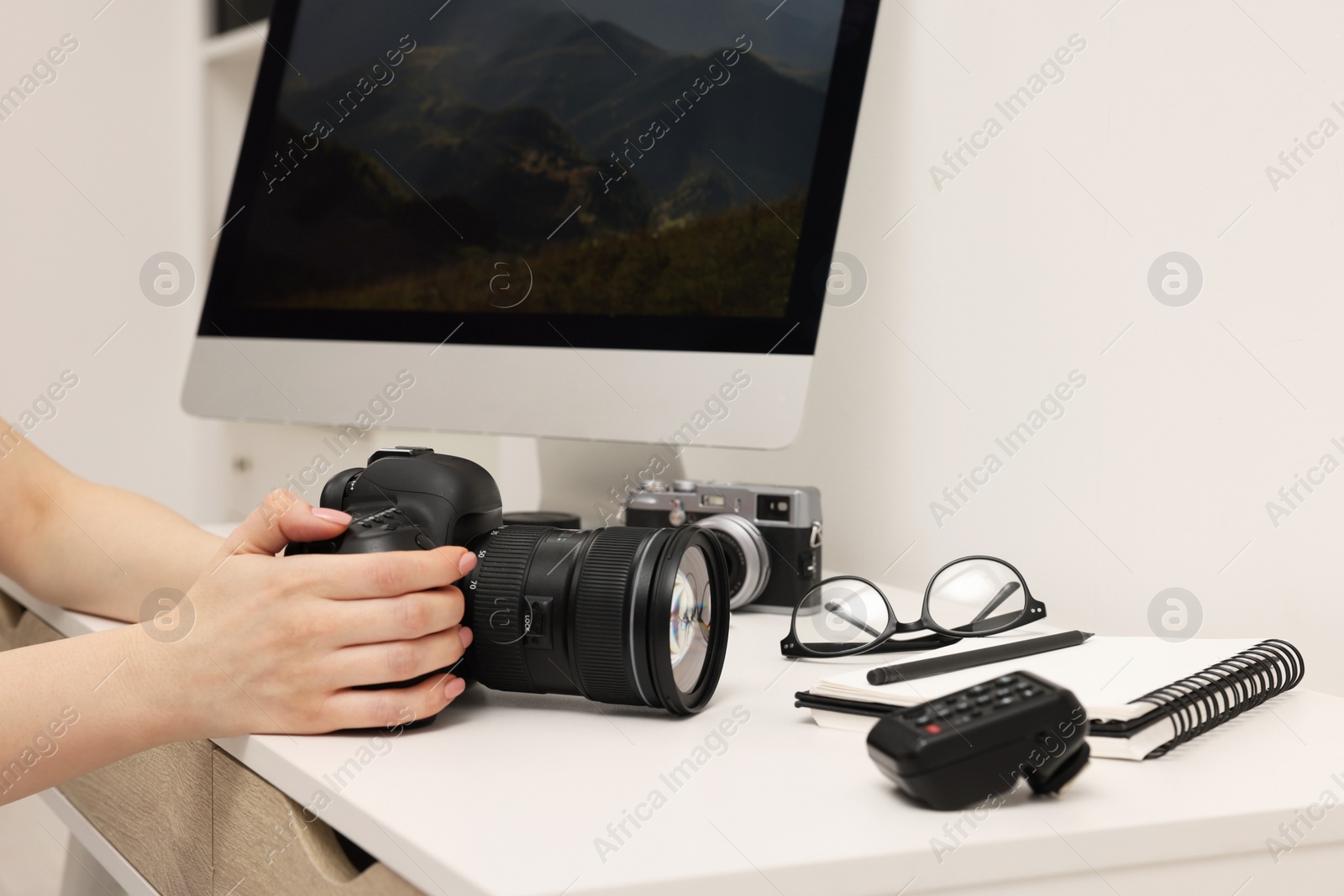 Photo of Photographer with camera at white table indoors, closeup