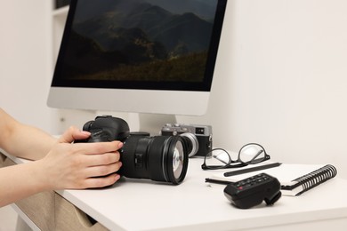 Photographer with camera at white table indoors, closeup