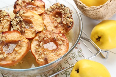 Delicious baked quinces with nuts in bowl and fresh fruits on table, closeup