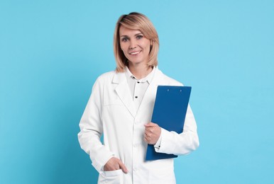 Photo of Smiling doctor with clipboard on light blue background