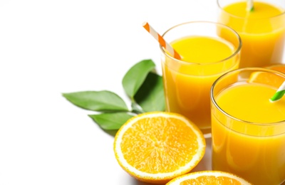 Photo of Glasses of orange juice and fresh fruits on white background, closeup