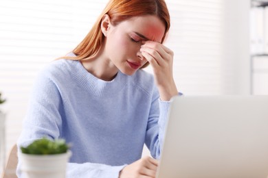 Young woman suffering from headache at home