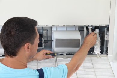 Technician repairing and checking air conditioner indoors