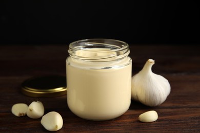 Photo of Jar of delicious mayonnaise and fresh garlic on wooden table