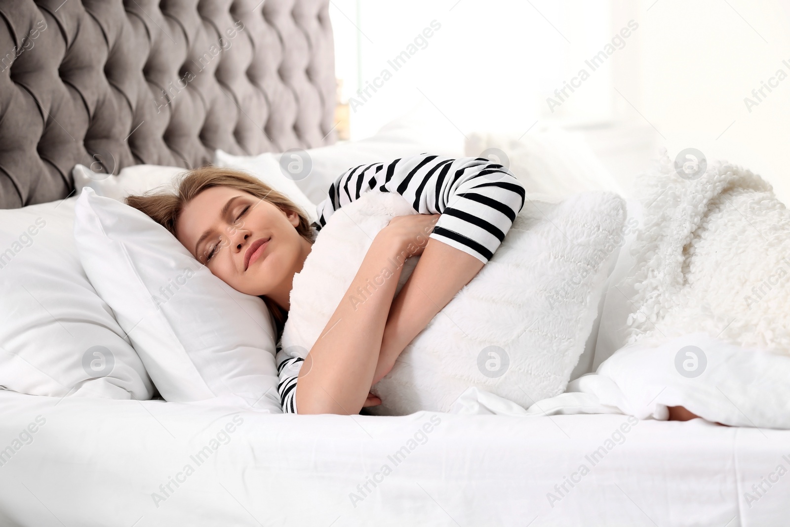 Photo of Young woman embracing pillow while sleeping in bed at home