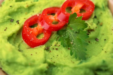 Delicious guacamole with chili pepper and parsley as background, closeup