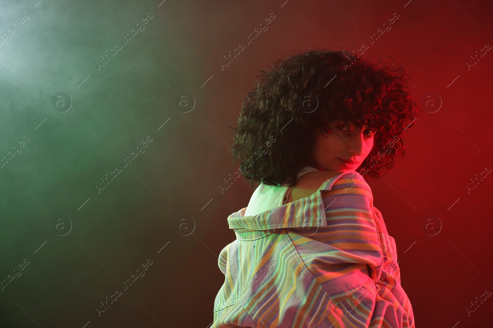 Photo of Beautiful young woman posing on color background in neon lights. Space for text