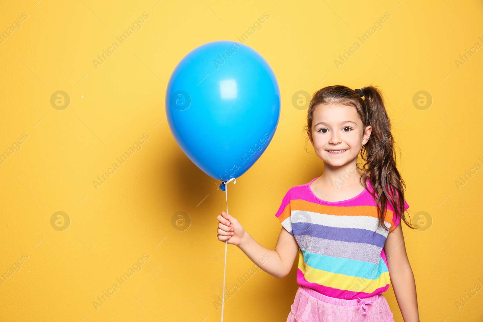 Photo of Cute girl with balloon on color background. Birthday celebration