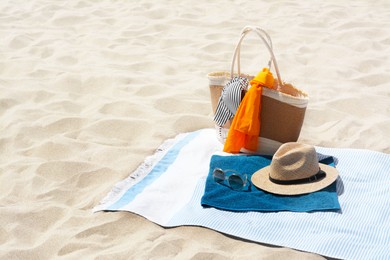 Photo of Blue blanket with towel, bag and beach accessories on sand. Space for text
