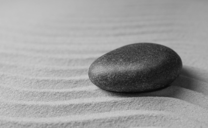 Photo of Zen garden stone on sand with pattern, space for text. Meditation and harmony