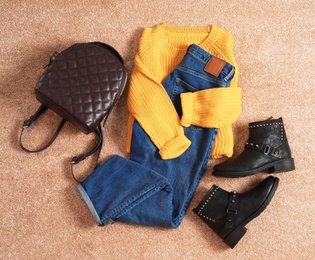 Flat lay composition with jeans, sweater and shoes on color fabric