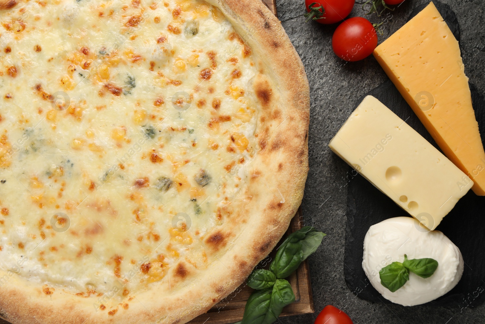 Photo of Delicious cheese pizza and ingredients on dark grey table, flat lay