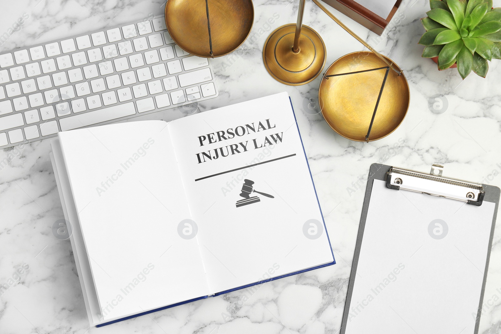 Photo of Flat lay composition with book, scales of justice and computer keyboard on marble background. Personal injury law concept