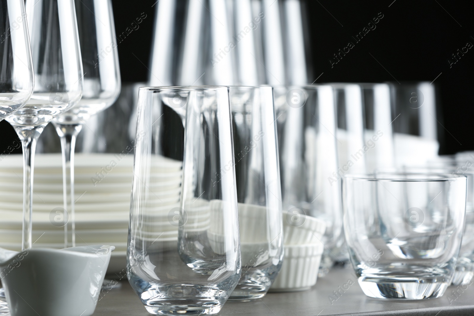 Photo of Set of empty glasses and dishware on table against black background