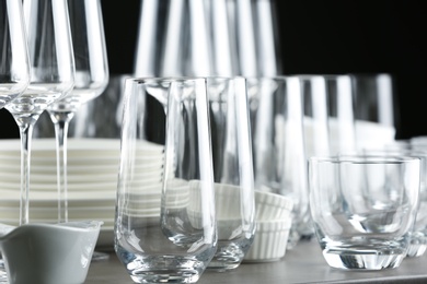 Set of empty glasses and dishware on table against black background