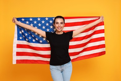 4th of July - Independence Day of USA. Happy woman with American flag on yellow background