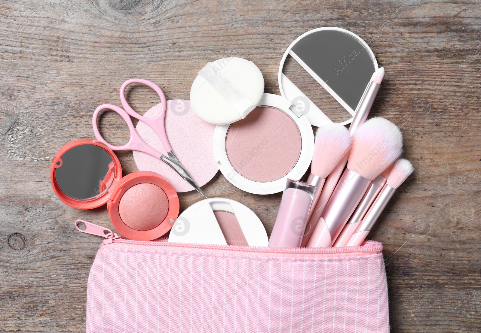 Photo of Cosmetic bag with makeup products and beauty accessories on wooden background, flat lay