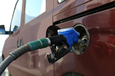 Modern car refilling with fuel at gas station, closeup
