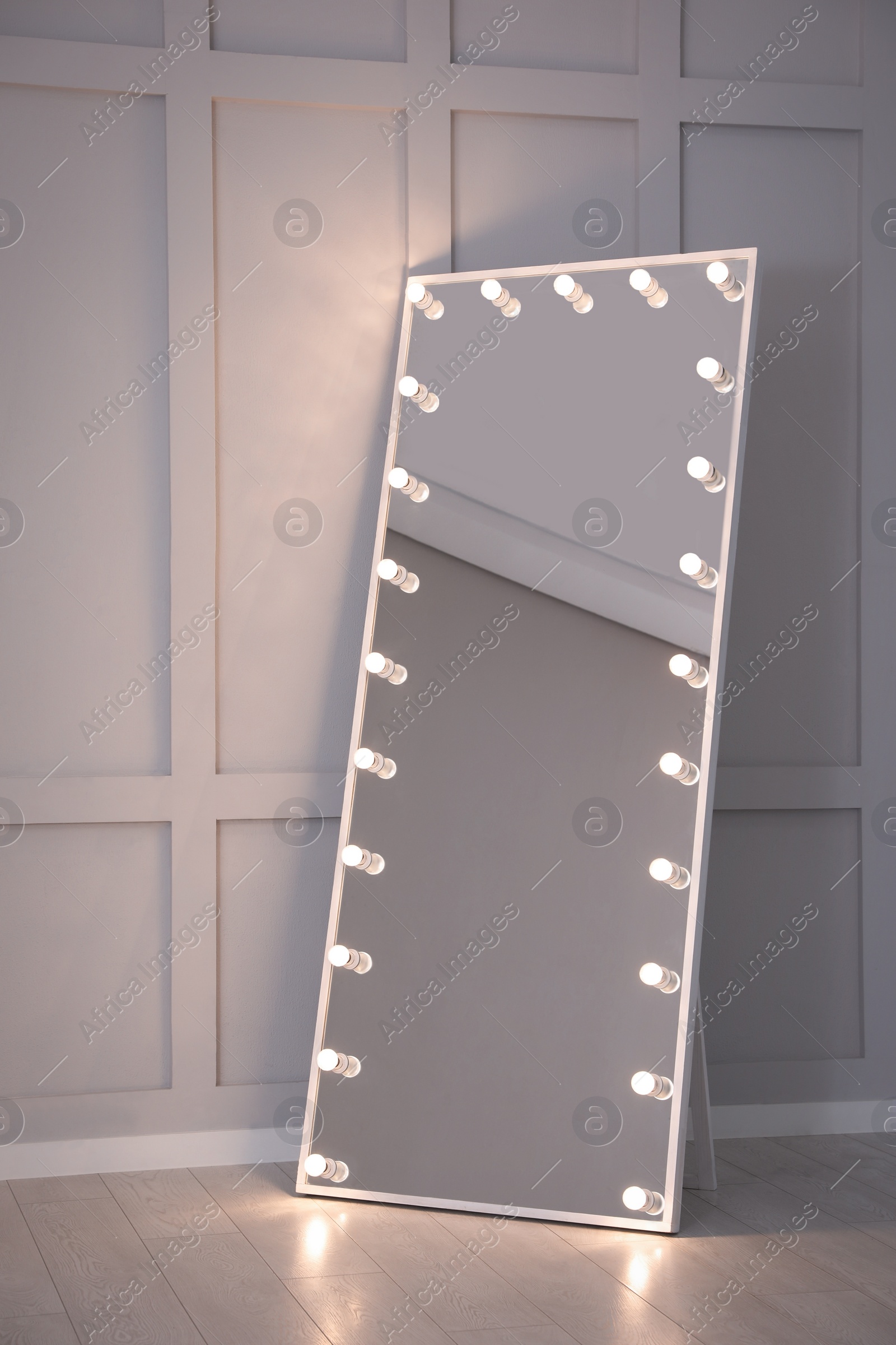Photo of Modern mirror with light bulbs near molding wall in room