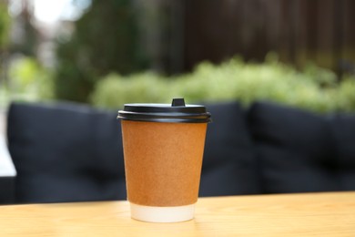 Paper cup on table in outdoor cafe. Coffee to go