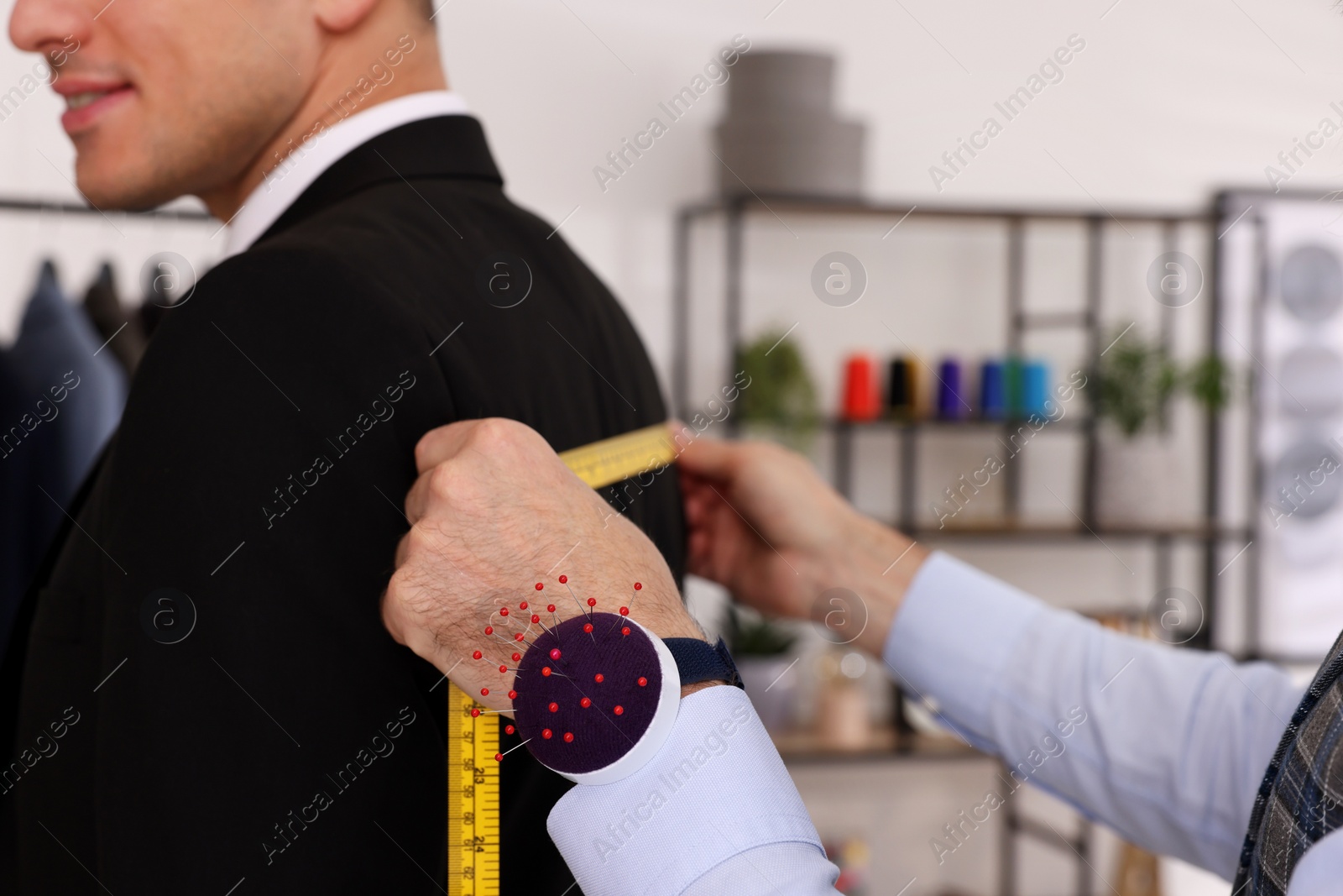 Photo of Professional tailor measuring client's back width in atelier, closeup