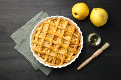 Tasty homemade quince pie and fresh fruits on black wooden table, flat lay