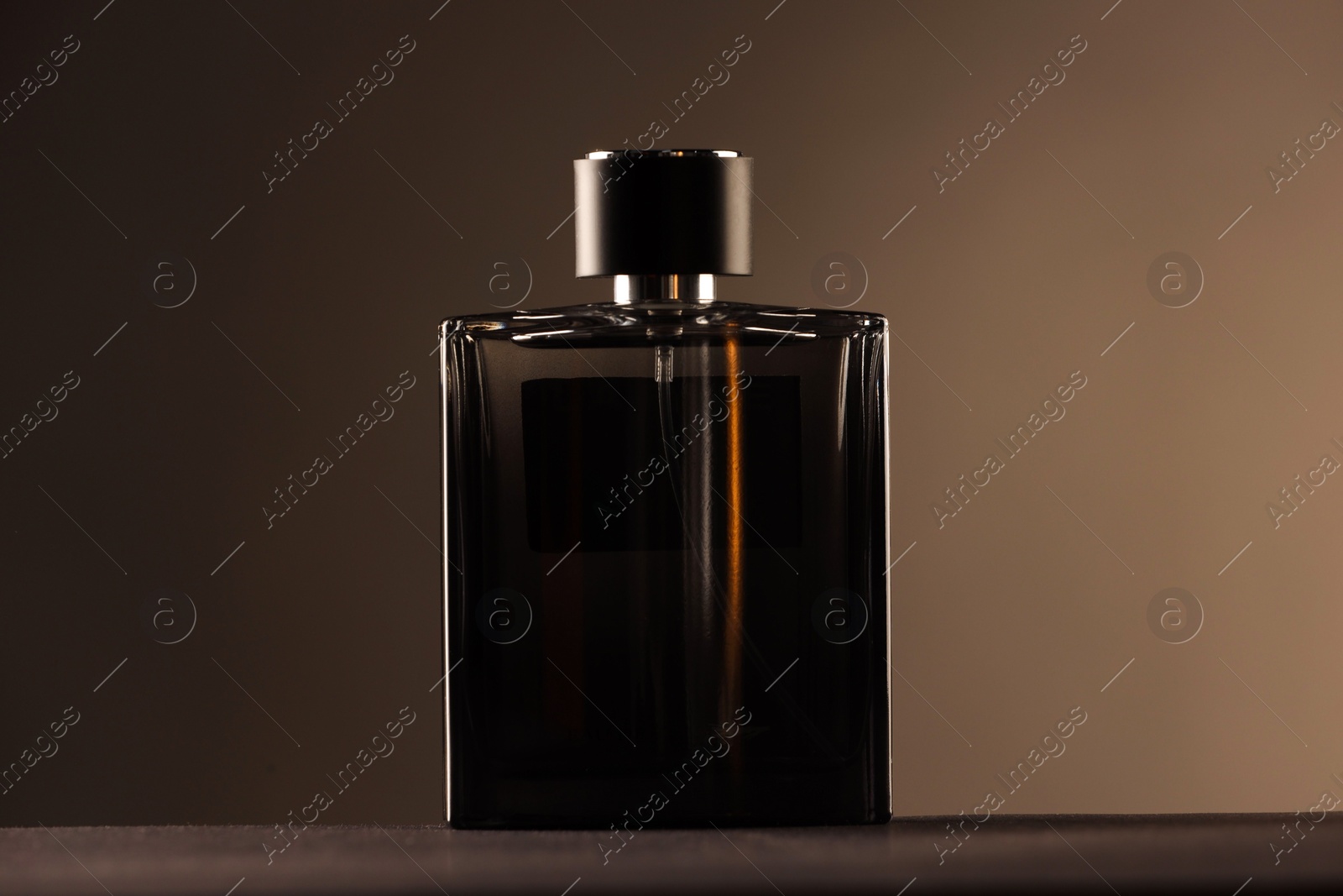 Photo of Luxury men`s perfume in bottle on table against color background