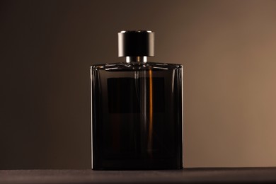 Photo of Luxury men`s perfume in bottle on table against color background