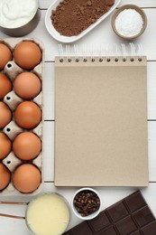 Photo of Blank recipe book and different ingredients on white wooden table, flat lay. Space for text