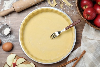 Photo of Flat lay composition with raw dough, fork and ingredients on wooden table. Baking apple pie