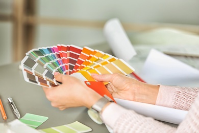 Photo of Female designer working with color palette samples at table