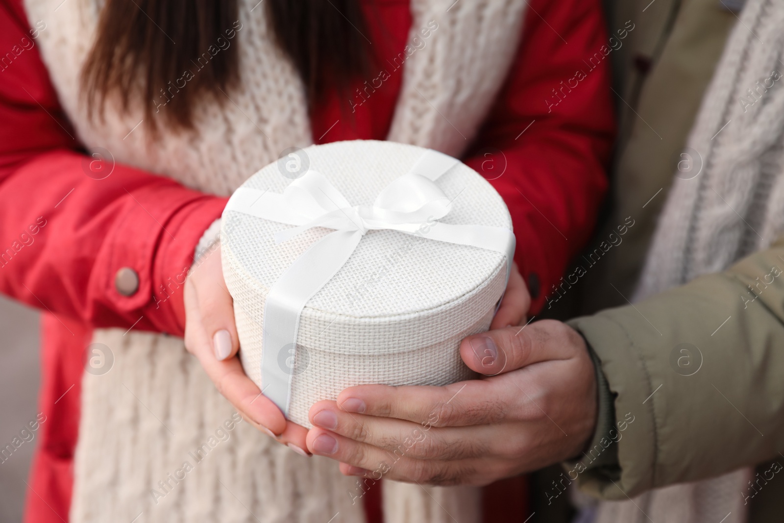 Photo of Happy young couple with gift box at winter fair, closeup. Christmas celebration