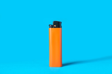 Photo of Orange plastic cigarette lighter on light blue background