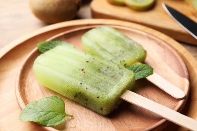 Photo of Plate of tasty kiwi ice pops on table, closeup. Fruit popsicle