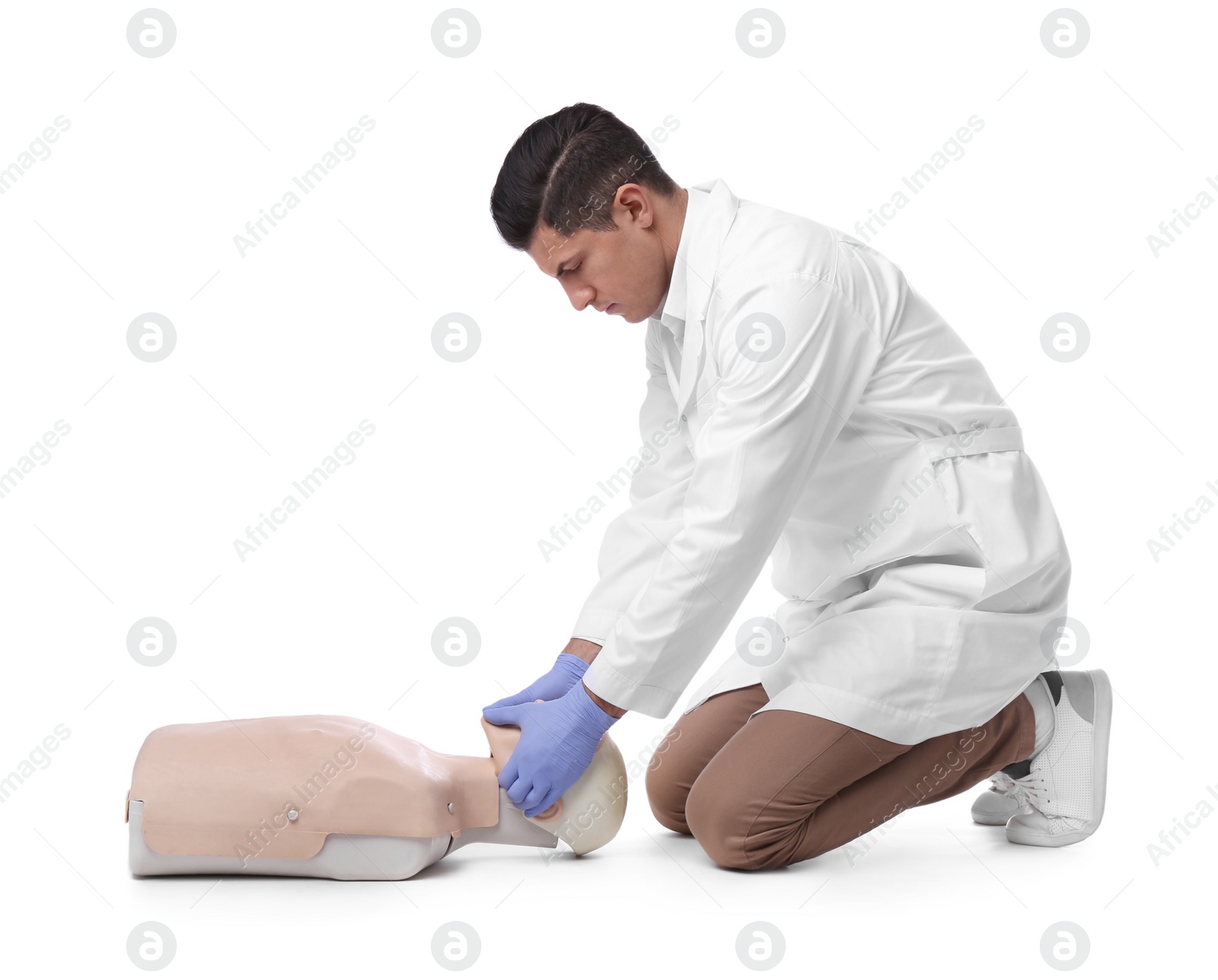 Photo of Doctor in uniform practicing first aid on mannequin against white background