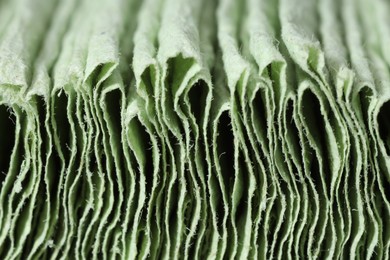 Texture of stacked light green paper napkins as background, macro view