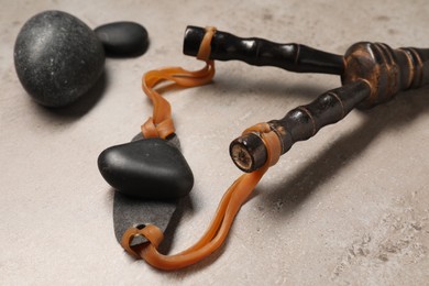 Black slingshot with stones on light grey table, closeup