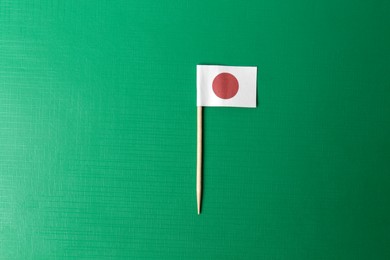 Photo of Small paper flag of Japan on green background, top view. Space for text