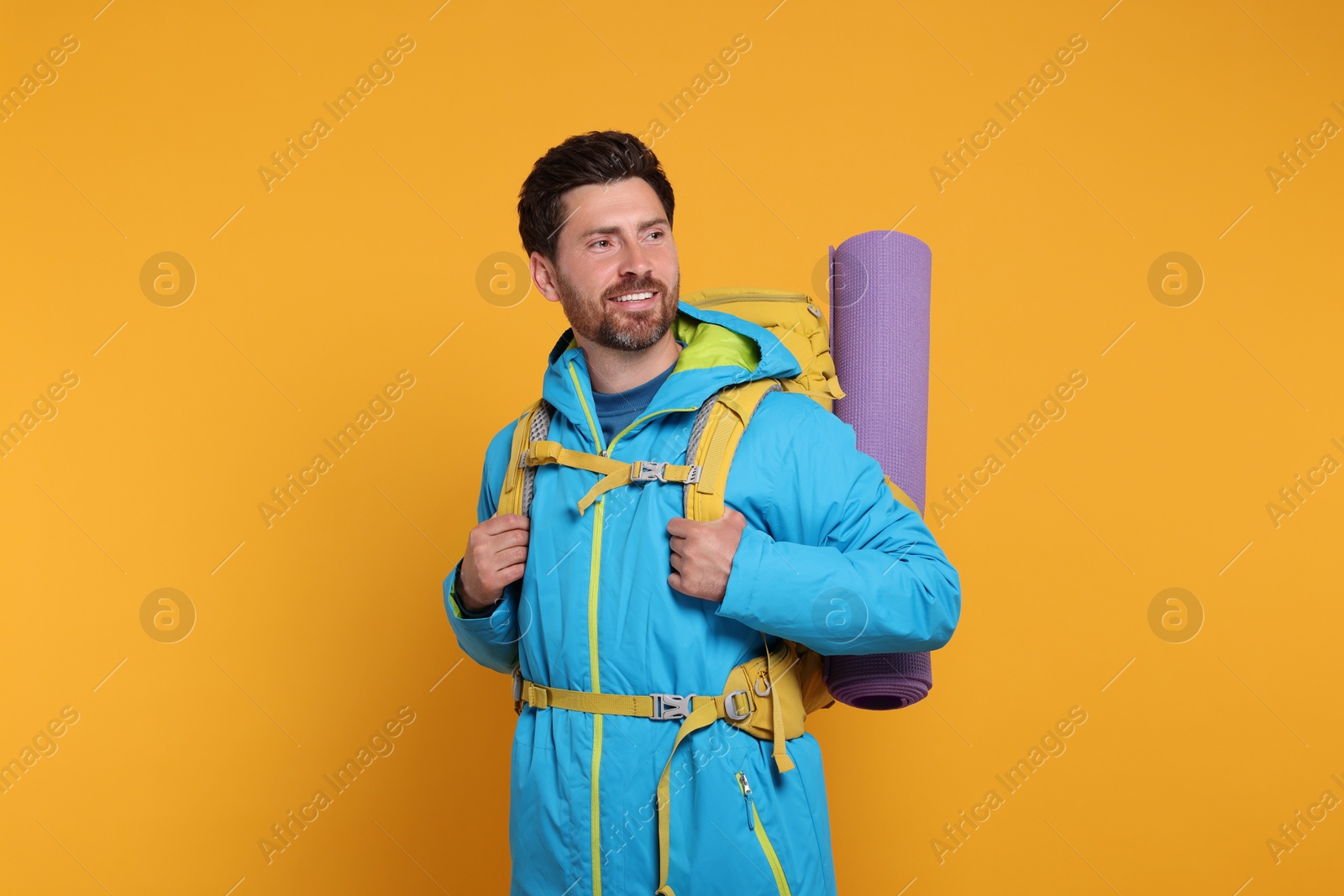 Photo of Happy man with backpack on orange background. Active tourism