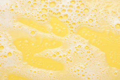 White washing foam on yellow background, top view