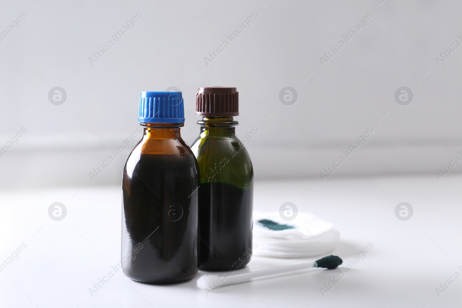 Photo of Bottles of brilliant green, cotton bud and pads on white table. Space for text