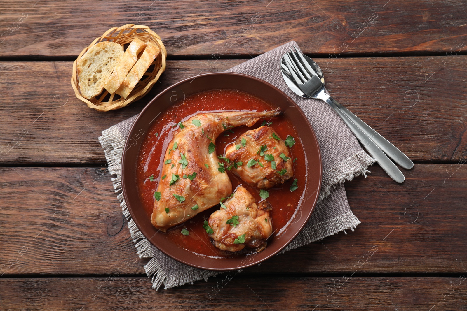 Photo of Tasty cooked rabbit meat with sauce served on wooden table, top view