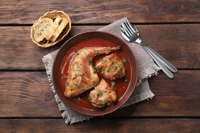 Tasty cooked rabbit meat with sauce served on wooden table, top view