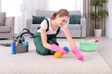 Photo of Female worker cleaning carpet at home