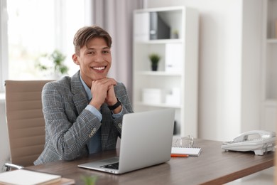 Photo of Man watching webinar at wooden table in office