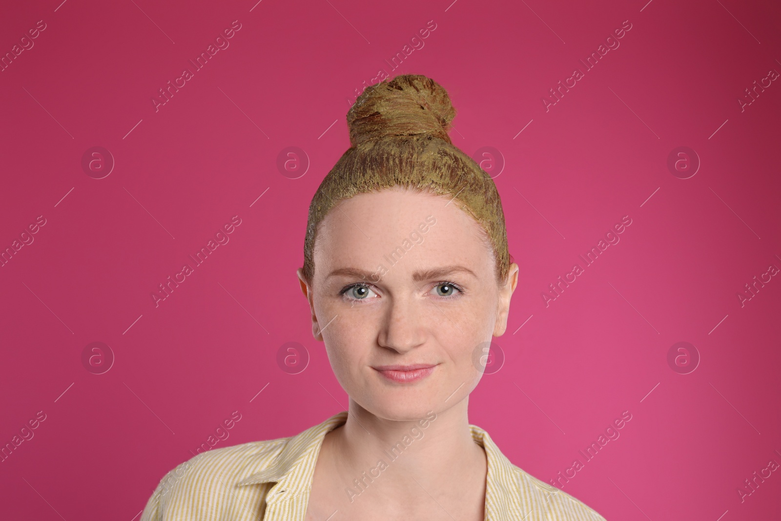 Photo of Young woman dyeing her hair with henna on pink background