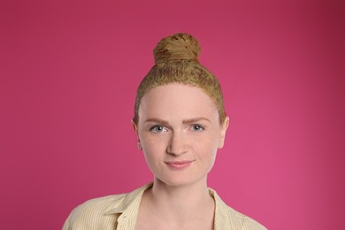 Photo of Young woman dyeing her hair with henna on pink background