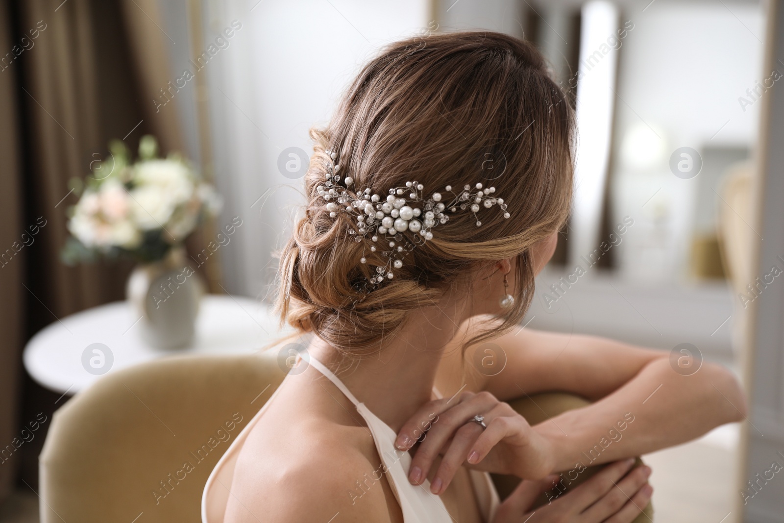 Photo of Young bride with elegant wedding hairstyle in room, back view